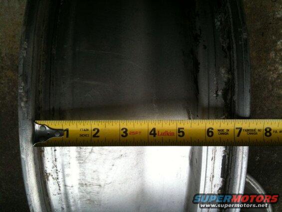 Close-up of a car wheel rim being measured with a tape measure.