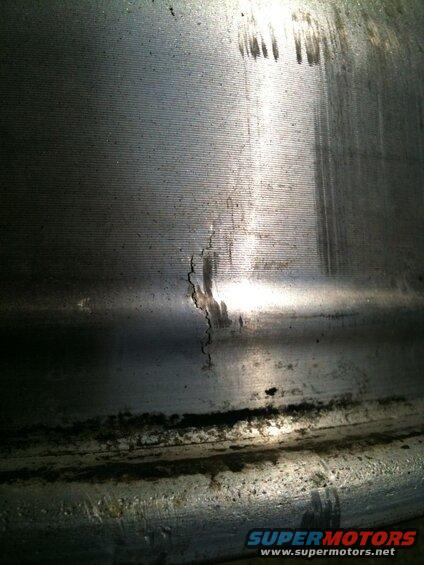 Close-up of a cracked metal wheel rim with horizontal lines and dirt.