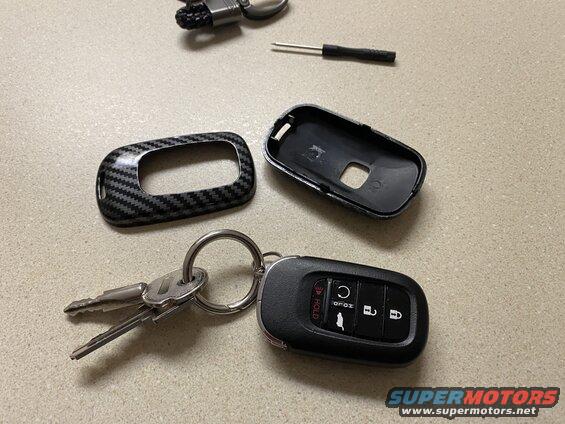 Car key fob disassembled with carbon fiber cover and keys.