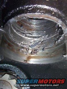 Close-up of a severely damaged engine bearing with metal shavings