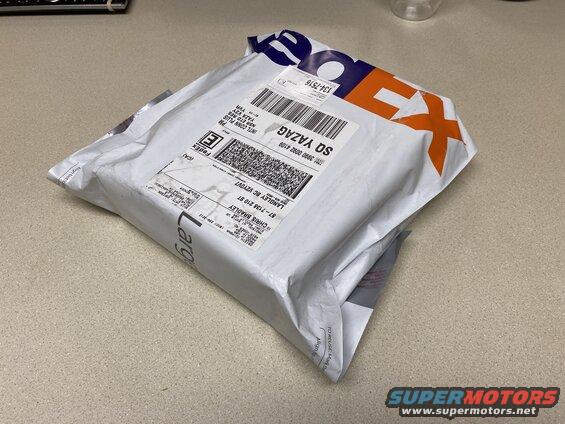White FedEx package on a speckled countertop.