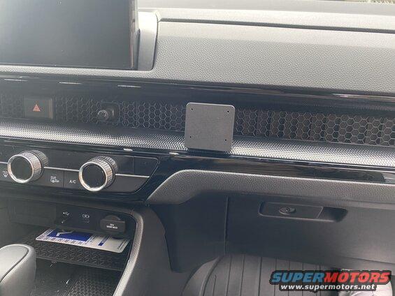 Car dashboard with phone mount on vent, climate controls, and USB ports.