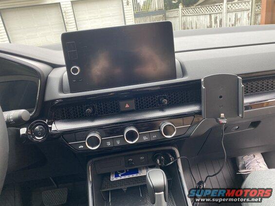 Car interior dashboard with infotainment screen, climate controls, and phone mount.
