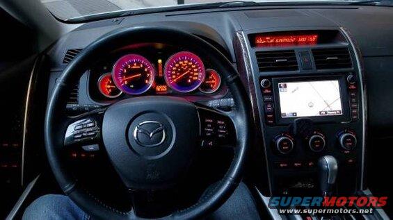 Interior view of a Mazda CX-9 dashboard with steering wheel, gauges, and navigation screen.