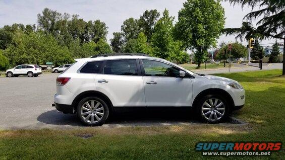Side view of a white 2009 Mazda CX-9 SUV parked on grass.