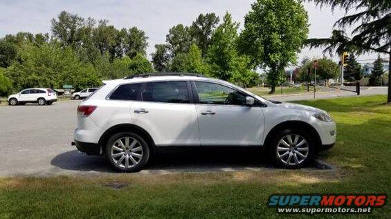 White 2009 Mazda CX-9 SUV parked on pavement with grass in foreground