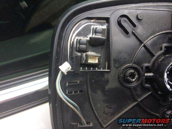 Back of a black side mirror housing with electrical connector and wires.