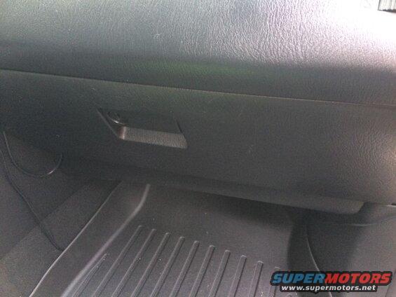 Interior view of a car's glove compartment and floor mat.