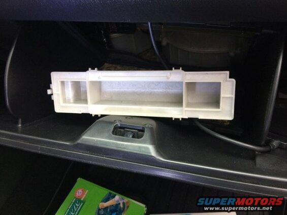 White plastic cabin air filter housing removed from a vehicle's glove compartment.