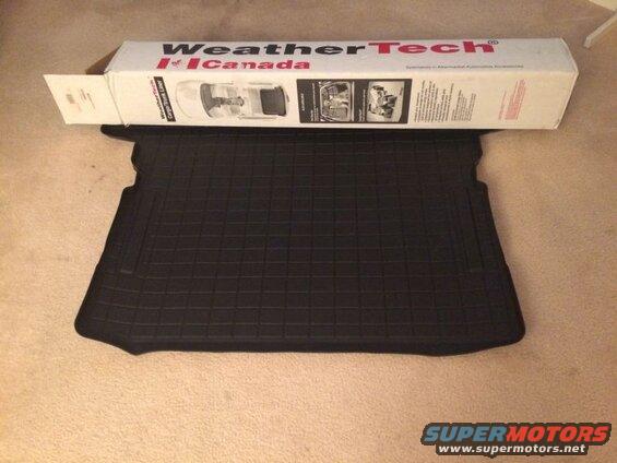 Black WeatherTech cargo liner with packaging box on carpet.