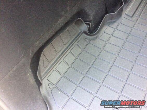 Black custom-fit cargo mat with grid pattern in a vehicle.