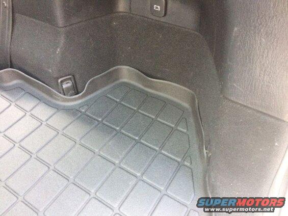 Close-up of a black, grid-patterned cargo mat in a vehicle's rear.