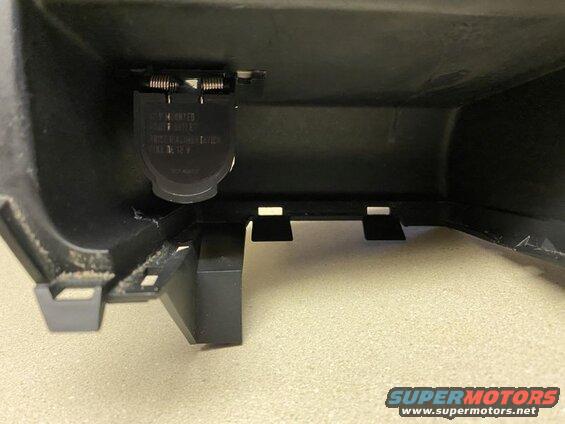 Interior view of a black plastic compartment with a 12V power outlet.