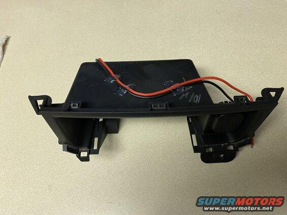 Black automotive trim piece with red and black wires attached with hot glue.