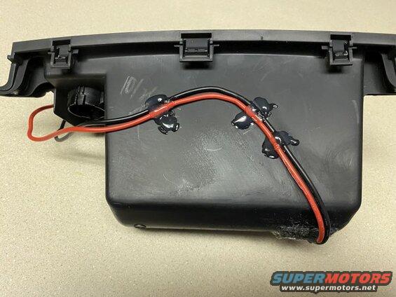 Black plastic housing with red and black wires attached by sealant.