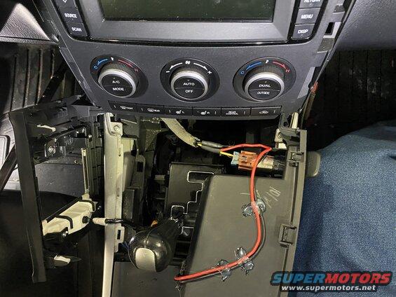 Disassembled car center console with exposed wiring and climate controls.