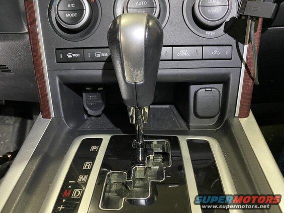 Close-up of a car's center console showing gear shifter, climate controls, and power outlets.