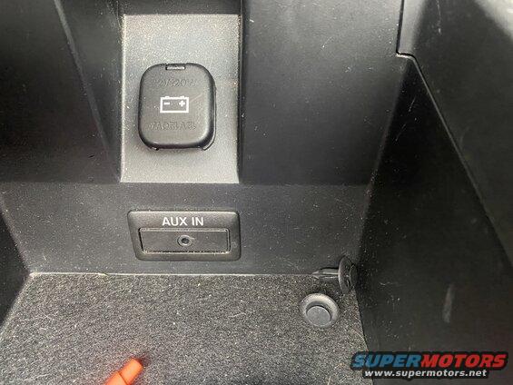 Vehicle center console with AUX IN port and 12V power outlet.