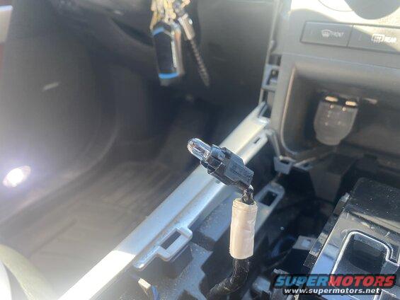 Close-up of a car interior showing a removed light bulb with a black connector.