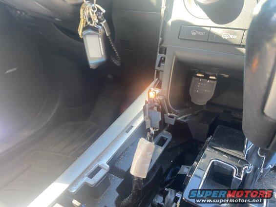 Car interior center console with charger port, gear shifter, and keys with remote fob.