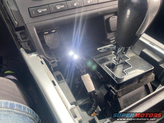 Center console of a car with gear shifter and LED lights.