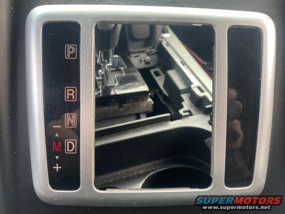 Close-up of a car's gear shifter console with P, R, N, M, D indicators visible.