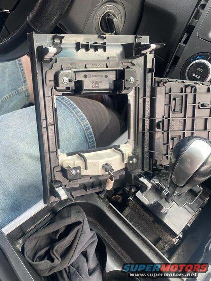 Disassembled car center console showing gear shifter, ignition, and trim.
