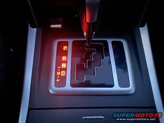 Close-up of a car's automatic transmission shifter showing 'M' gear selected.