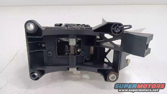 Black plastic automotive shifter assembly or bracket with visible linkage and zip tie.