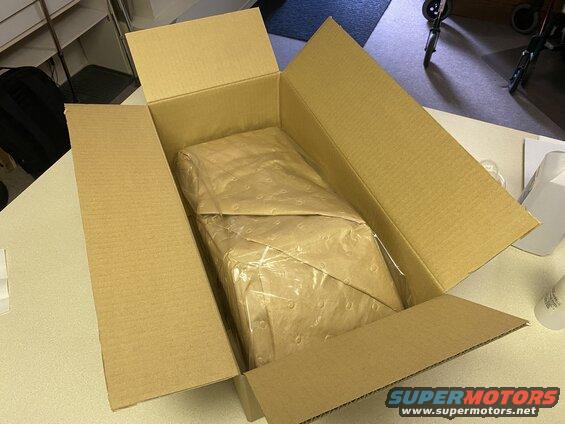 Cardboard shipping box open on a table, with a wrapped item inside.