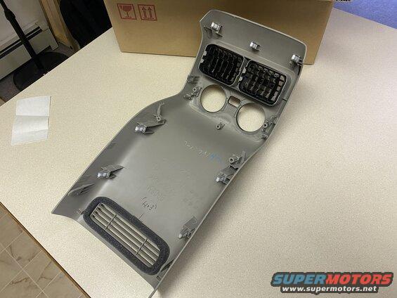 Gray plastic vehicle interior trim piece with air vents and circular cutouts.