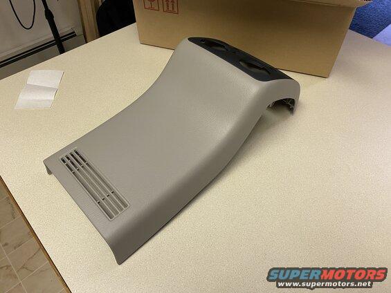 Gray plastic interior trim piece with vent and circular cutouts