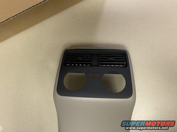Gray and black automotive interior part with air vents and circular cutouts