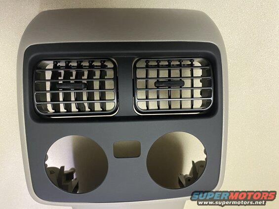 Rear passenger climate control vents and circular openings on a vehicle interior trim piece.