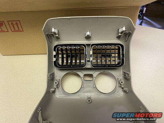 Tan dashboard trim piece with two air vents and two circular cutouts.