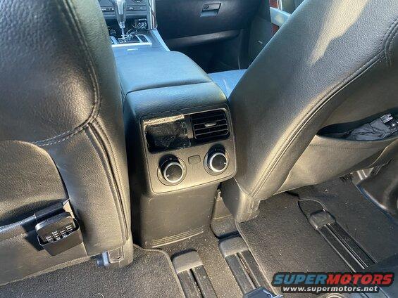 Interior of a car showing rear climate controls, seats, and a USB charger.
