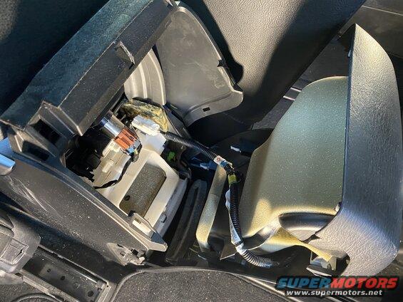 Disassembled car center console showing wiring, connectors, and foam insulation.