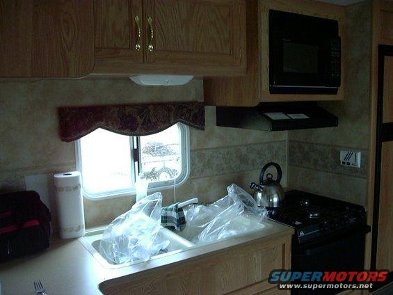 RV kitchen with sink, faucet, paper towel holder, microwave, and stove