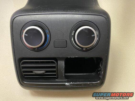 Rear climate control panel with two knobs, air vent, and open slot.