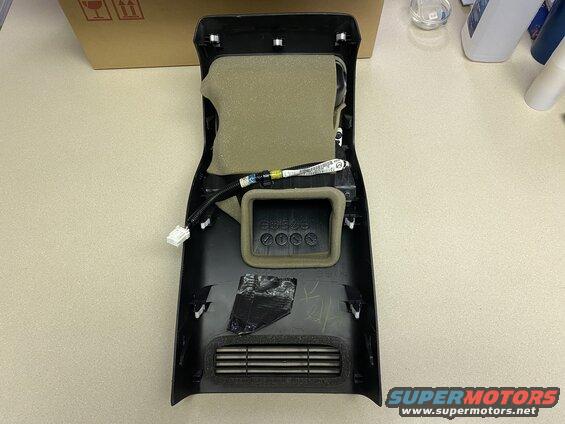 Interior of a black plastic vehicle trim piece with foam, wiring, and a vent.