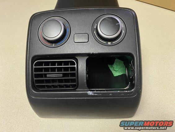 Black automotive center console climate control knobs, air vent, and cubby