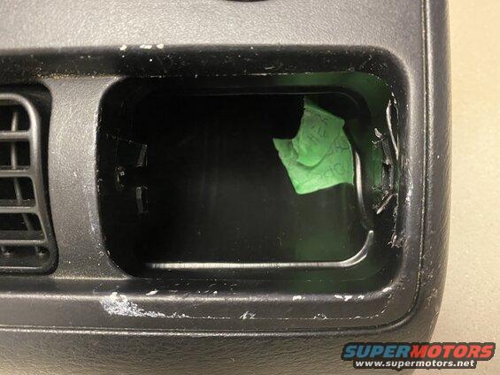Interior car dashboard compartment with green tape and scratches.
