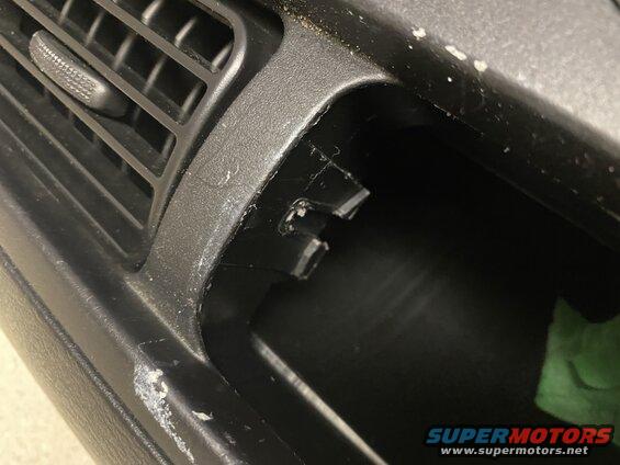 Close-up of a black car dashboard vent and open storage compartment.