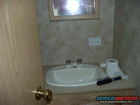Bathroom sink area with a roll of toilet paper and a hairbrush on the counter