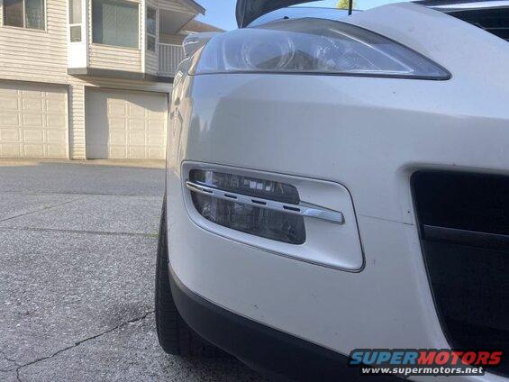 White SUV front bumper and headlight with chrome fog light accent.