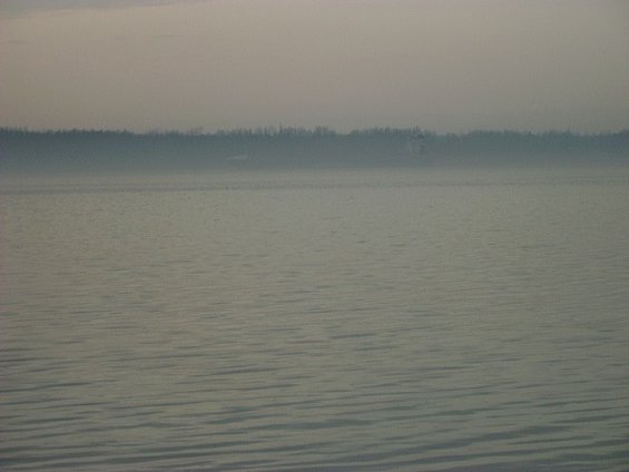 calm water with a distant treeline under a hazy sky. Supermotors logo in the corner