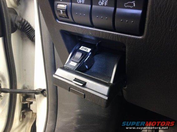 Close-up of a DRL switch in a car dashboard compartment.