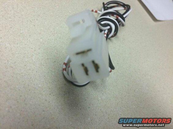 White electrical plug with coiled black and white wires on a speckled countertop.