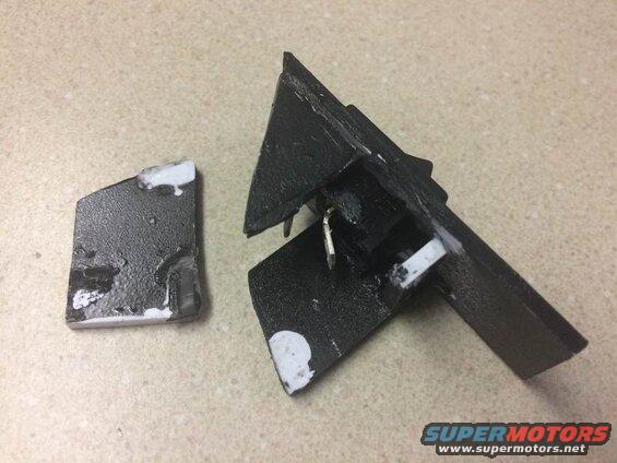 Broken black plastic car part with white adhesive