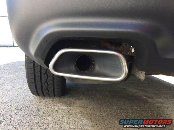 Close-up of a black SUV's exhaust tip with chrome trim and rear bumper.